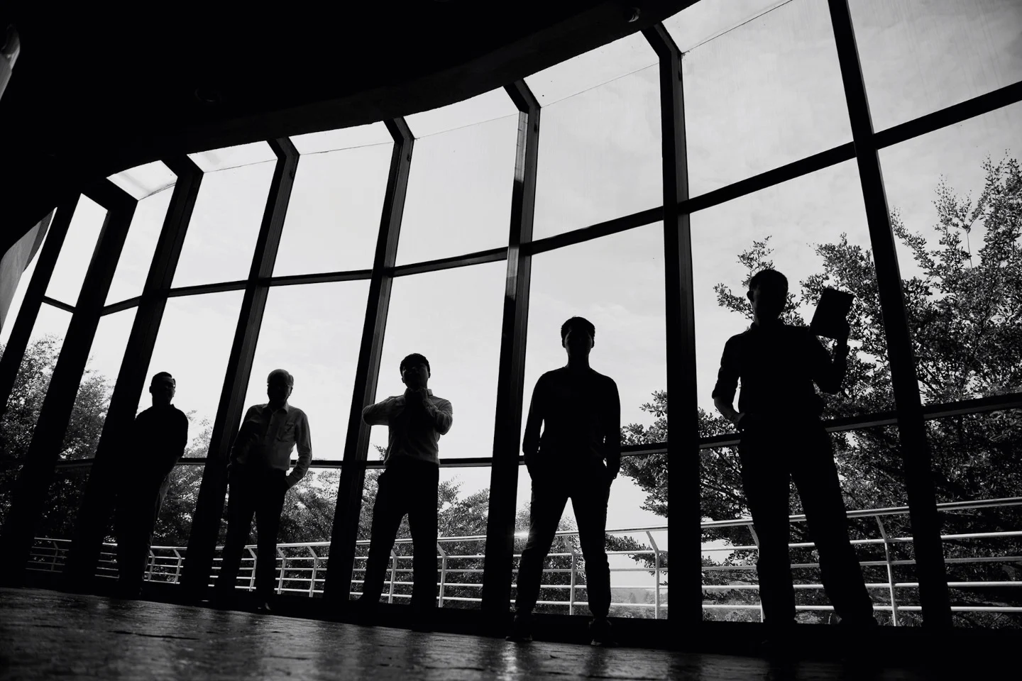 The Valse team in silhouette against a curved glass wall